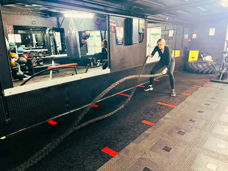 A client doing battle rope slams at the gym