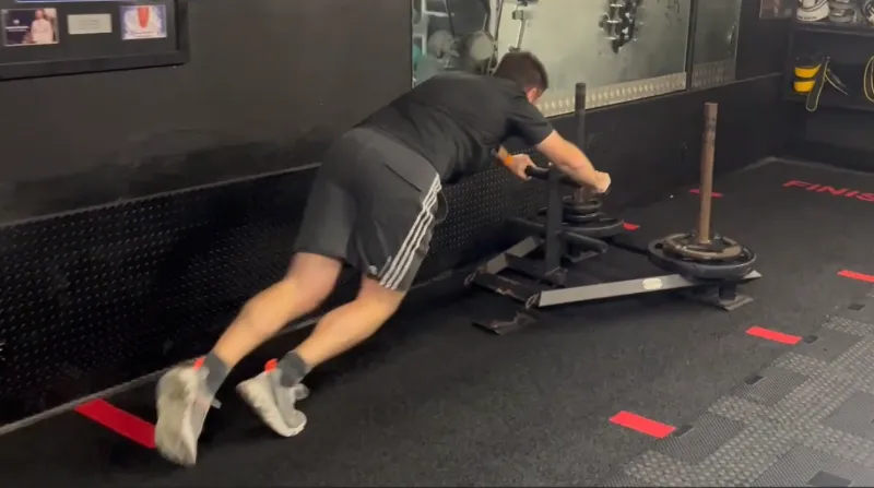 A client pushing a sled at the gym