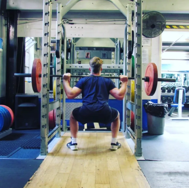 A client squatting in a rack at the gym